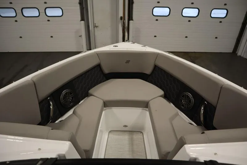 Slide: The Image of 2025 Four Winns H2 boat interior with cushioned seating and speakers in a garage. - 19