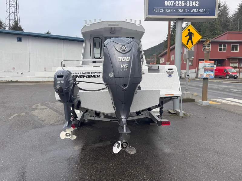 Slide: The Image of 2025 KingFisher 2625 Coastal Express boat with dual outboard motors in a parking lot. - 2