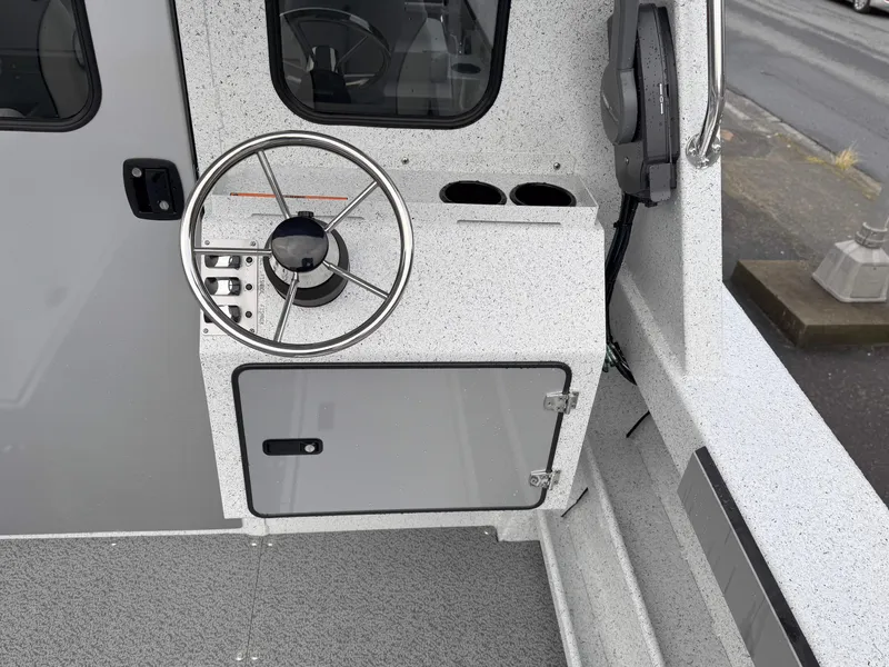 Slide: The Image of 2025 KingFisher 2625 Coastal Express boat helm with steering wheel and storage compartment. - 7