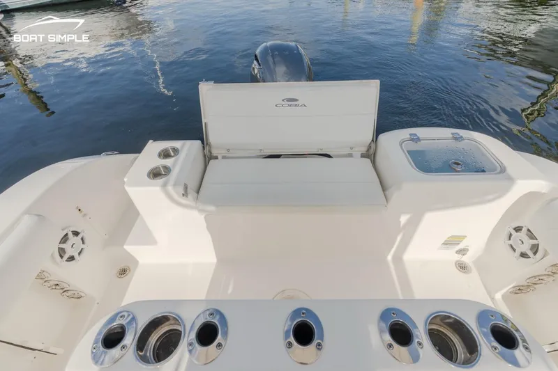 Slide: The Image of 2022 Cobia 201 Center Console boat with rod holders and storage, docked on calm water. - 6