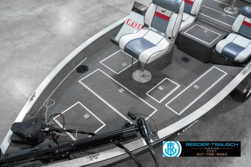 Slide: The Image of 1990 Lowe 1700 boat interior with seating and storage compartments, displayed in a showroom. - 10