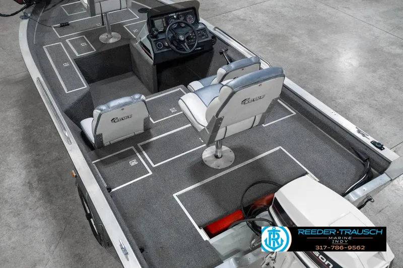 Slide: The Image of 1990 Lowe 1700 boat interior with seating and steering console, displayed in a showroom. - 13