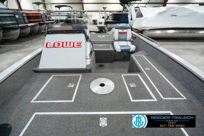 Slide: The Image of 1990 Lowe 1700 boat interior with seating and storage, displayed in a showroom. - 17