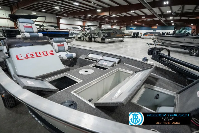 Slide: The Image of 1990 Lowe 1700 boat interior with open storage compartments in a showroom. - 22