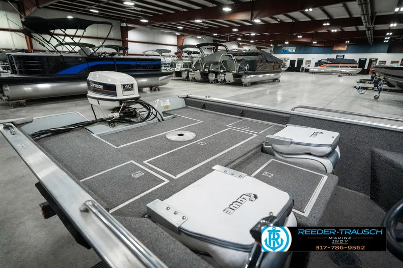 Slide: The Image of 1990 Lowe 1700 boat interior with motor, displayed in a spacious showroom. - 24