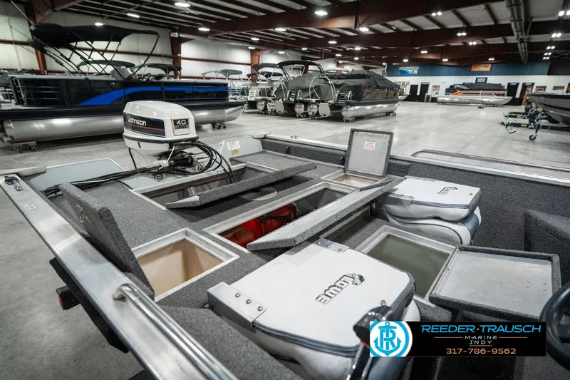 Slide: The Image of 1990 Lowe 1700 boat interior with storage compartments and motor in a showroom. - 25