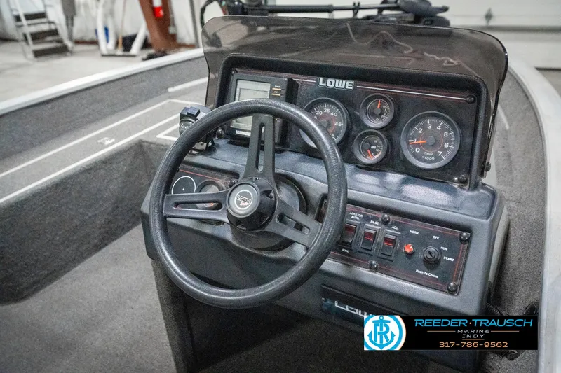 Slide: The Image of 1990 Lowe 1700 boat dashboard with steering wheel and instrument panel. - 26