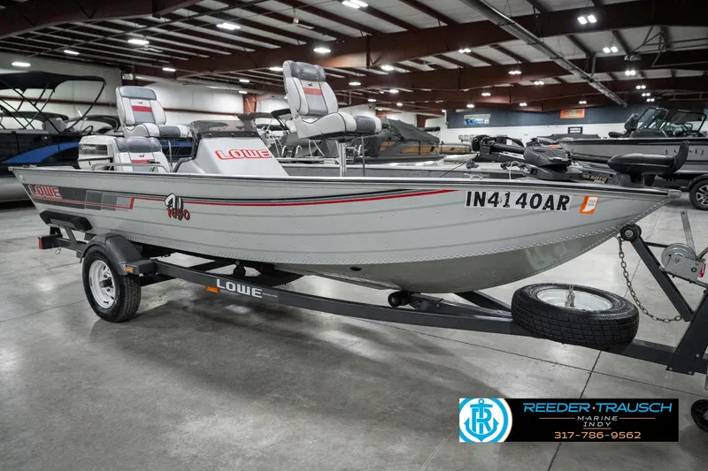 Slide: The Image of 1990 Lowe 1700 boat on trailer in indoor showroom, featuring seating and registration number IN4140AR. - 4