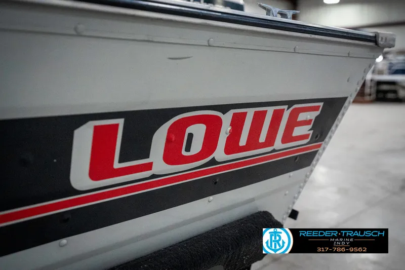 Slide: The Image of 1990 Lowe 1700 boat with bold red logo in a showroom setting. - 44