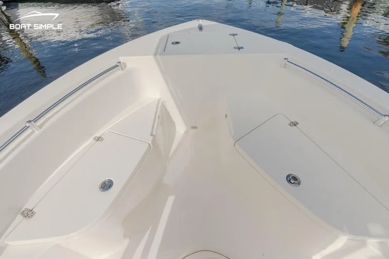 Slide: The Image of 2022 Cobia 201 Center Console boat deck with storage compartments, docked on calm water. - 10
