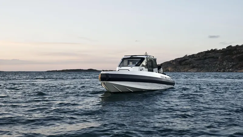 Slide: The Image of Iron 827C boat on open water, 2025 model, near rocky shoreline at sunset. - 6