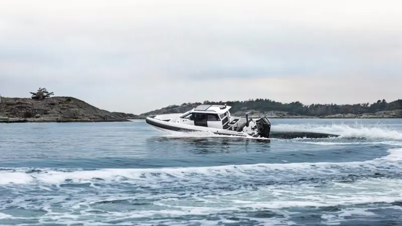 Slide: The Image of 2025 Iron 827C boat cruising on a serene lake with rocky shoreline. - 9