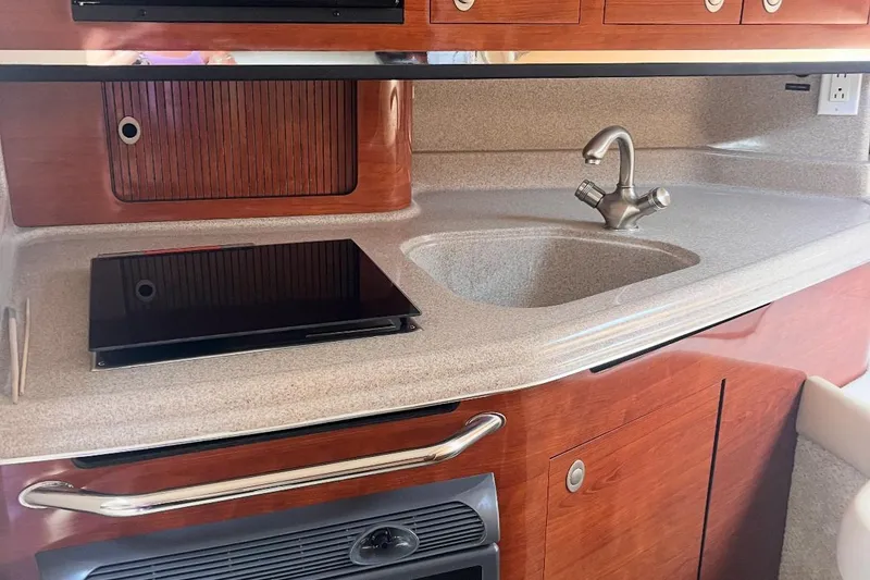 Slide: The Image of 2007 Sea Ray Amberjack kitchen with sink, stovetop, and wooden cabinetry. - 28