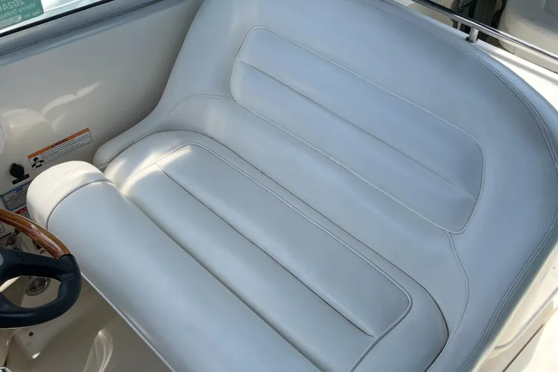 Slide: The Image of 2007 Sea Ray Amberjack boat seat with white leather upholstery and wooden steering wheel. - 34