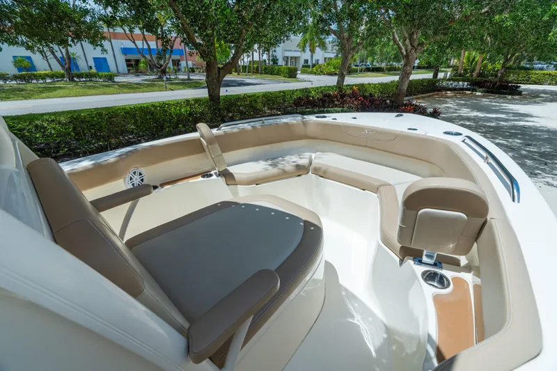 Slide: The Image of 2023 Scout 215 XSF boat interior with cushioned seating and cup holders, parked outdoors. - 10