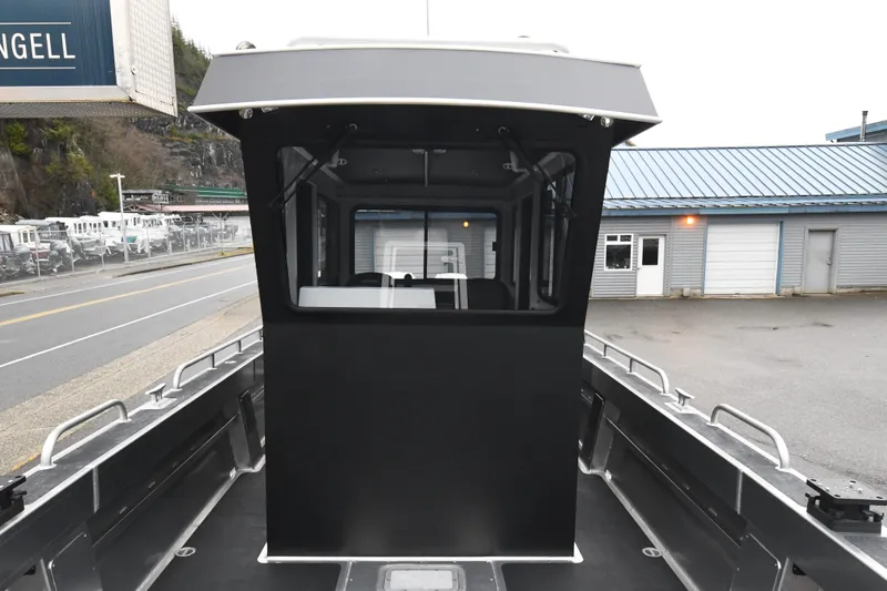 Slide: The Image of Custom 2025 model 24 LC boat with enclosed cabin, docked near industrial buildings. - 13