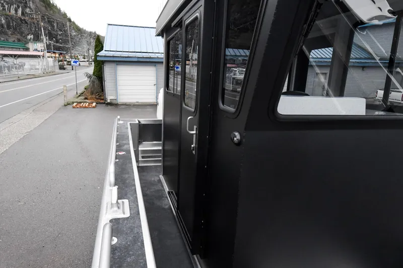 Slide: The Image of Custom 2025 model 24 LC boat exterior, docked near a road and buildings. - 15