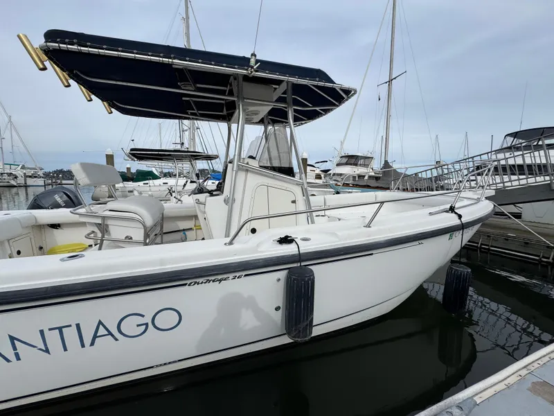 Slide: The Image of 2001 Boston Whaler 26 Outrage boat docked in marina, featuring a sleek design and canopy. - 11