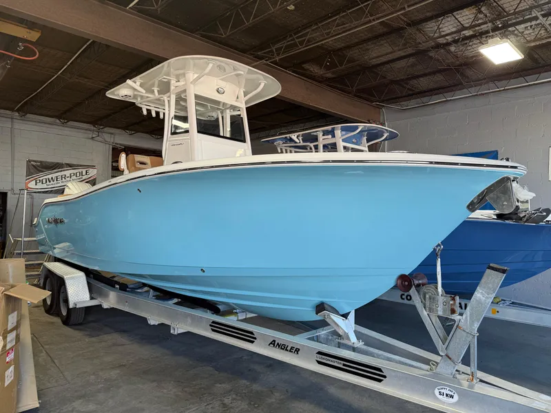Slide: The Image of 2025 NauticStar 252 Legacy boat in a showroom, displayed on a trailer. - 1