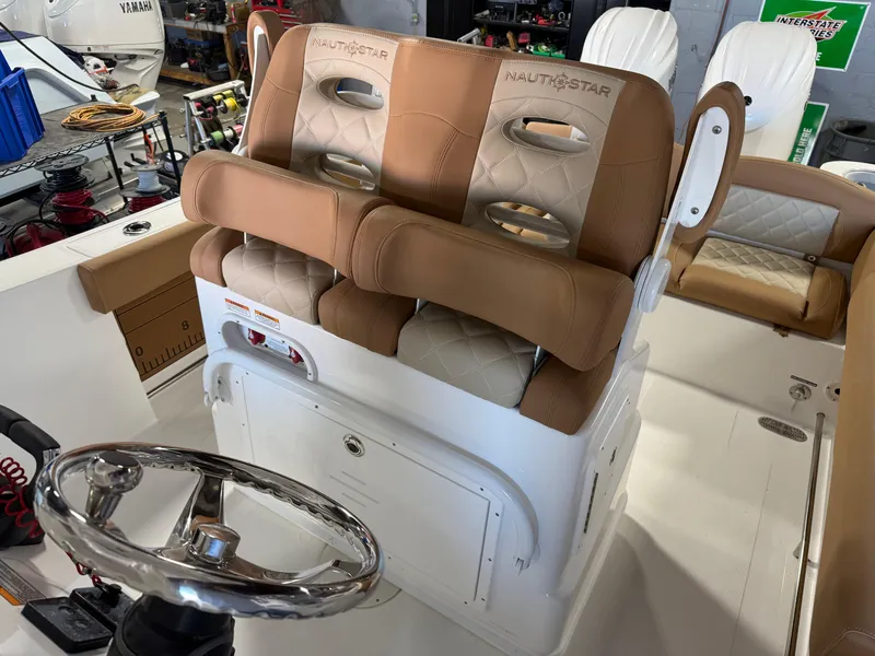 Slide: The Image of 2025 NauticStar 252 Legacy boat interior with dual tan seats and steering wheel. - 15