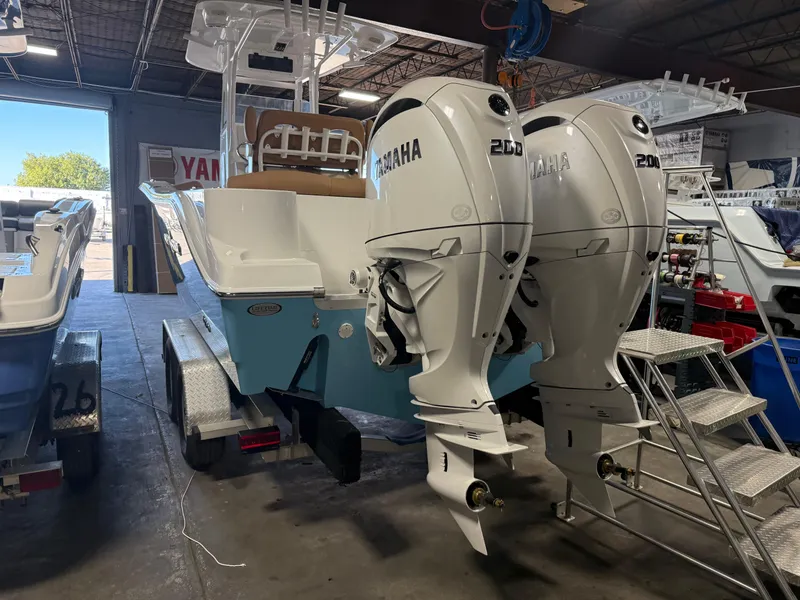 Slide: The Image of 2025 NauticStar 252 Legacy boat with twin Yamaha 200 engines in a showroom. - 2