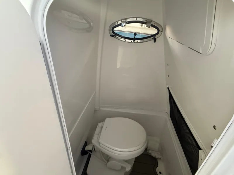 Slide: The Image of 2025 NauticStar 252 Legacy boat interior with compact marine toilet and porthole. - 3