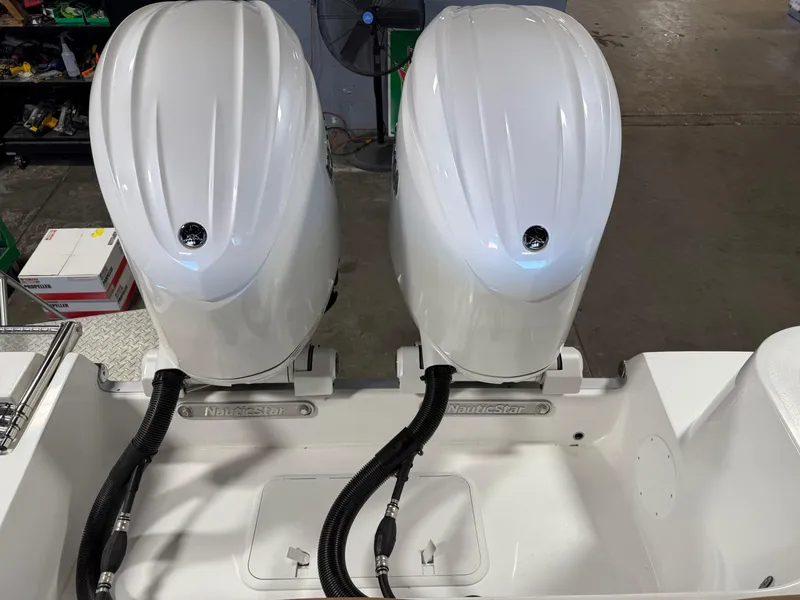 Slide: The Image of 2025 NauticStar 252 Legacy boat with dual outboard motors in a workshop setting. - 7