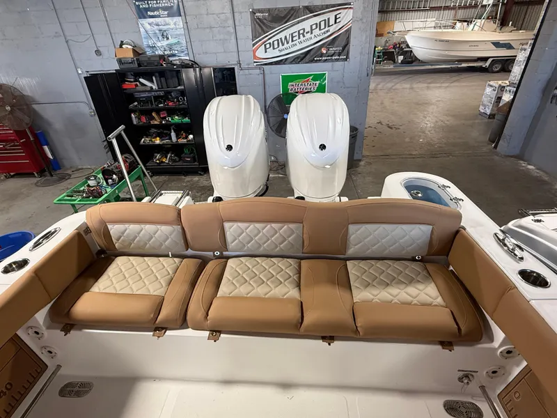 Slide: The Image of 2025 NauticStar 252 Legacy boat with tan seating and dual engines in a garage setting. - 8