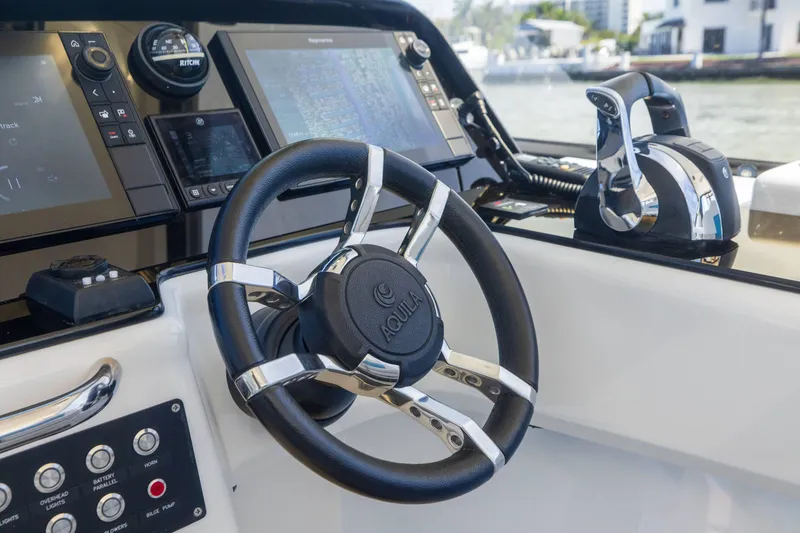 Slide: The Image of Steering console of 2019 Aquila 36 Sport boat with modern controls and navigation screens. - 16