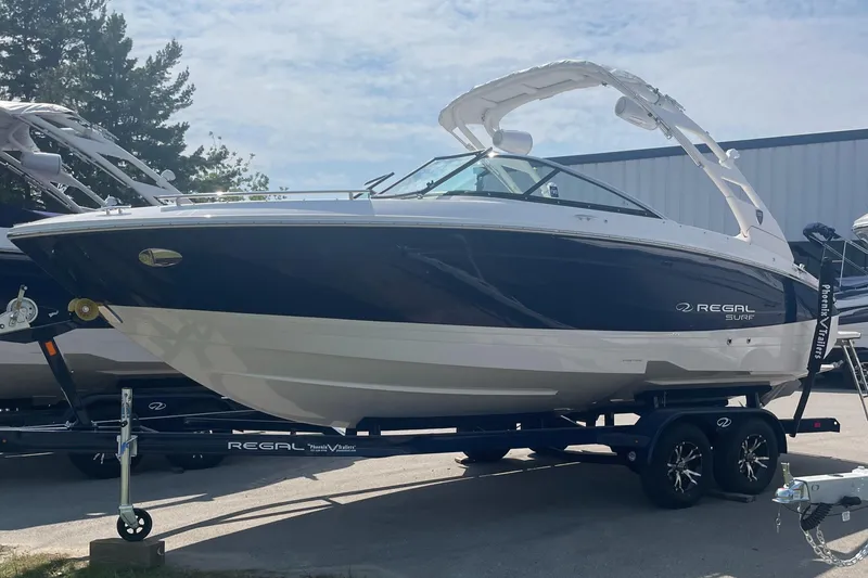The Image of 2025 Regal LS4 Surf boat on trailer, sleek design, parked outdoors. - 0