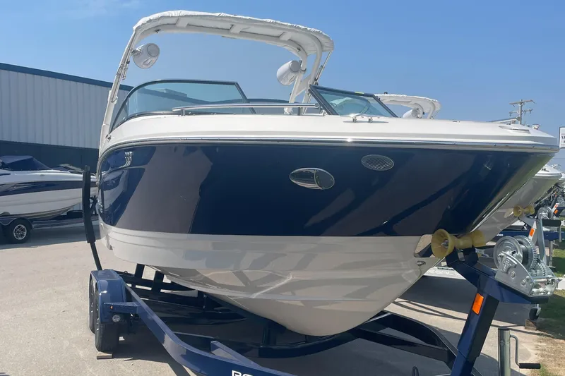 Slide: The Image of 2025 Regal LS4 Surf boat on trailer, blue and white design, parked outdoors. - 2