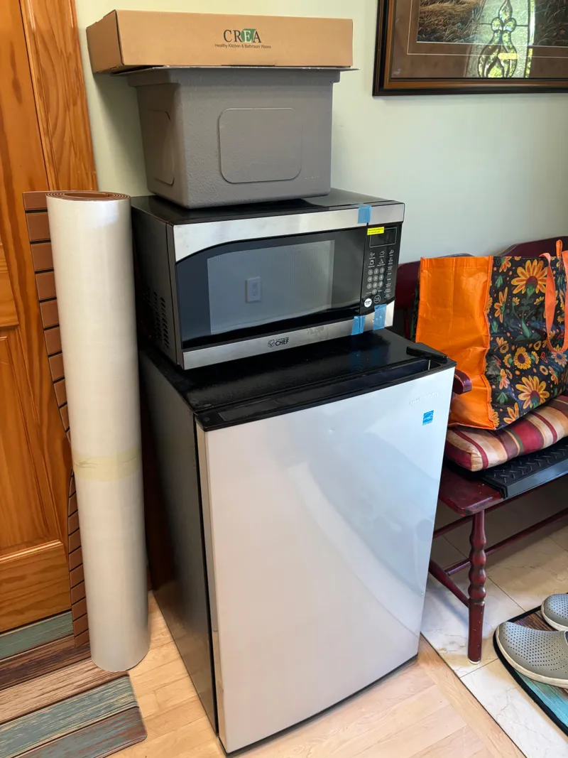 Slide: The Image of Mini fridge with microwave on top, surrounded by storage items in a cozy room. - 14