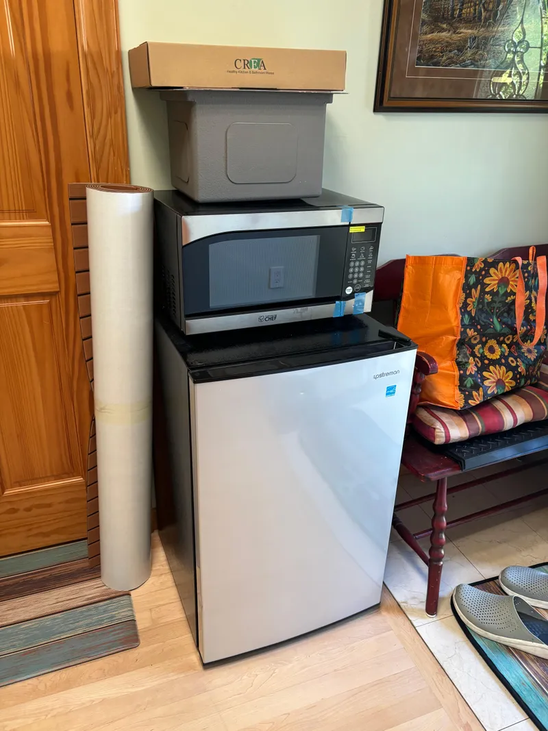 Slide: The Image of Mini fridge with microwave and storage boxes in a cozy room corner. - 15