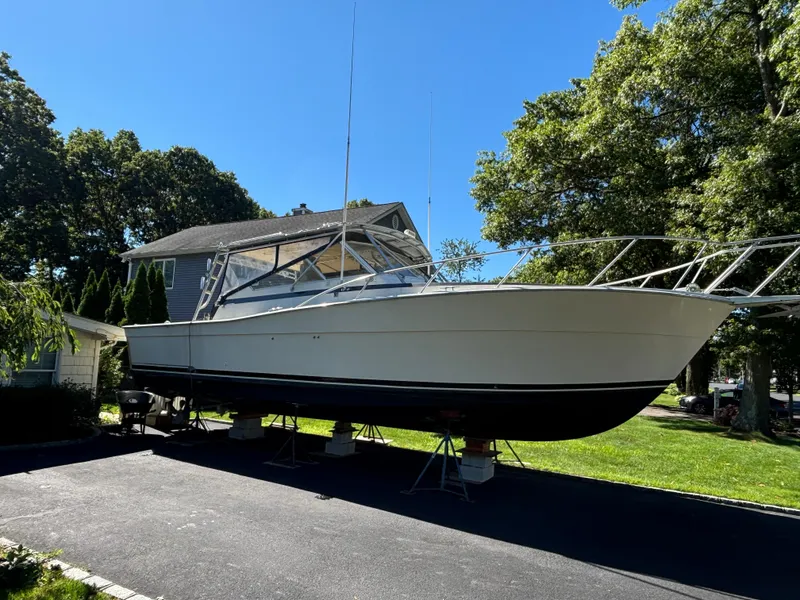 Slide: The Image of 1984 Viking Express Cruiser boat on a driveway, surrounded by trees and a house. - 3