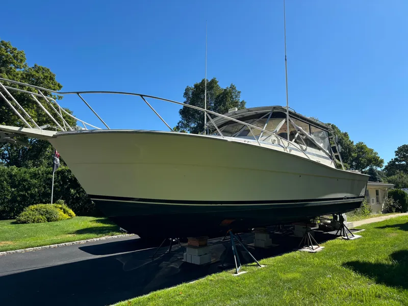 Slide: The Image of 1984 Viking Express Cruiser boat on stands, outdoors, under clear blue sky. - 4