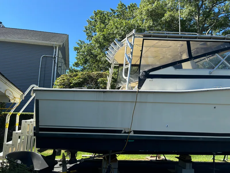 Slide: The Image of 1984 Viking Express Cruiser boat on land near a house, under clear blue sky. - 5