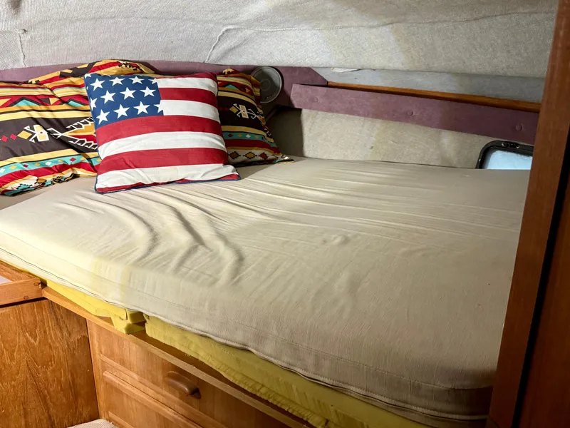 Slide: The Image of 1986 Cruisers Yachts 297 Elegante cabin with bed, colorful pillows, and wooden storage. - 15