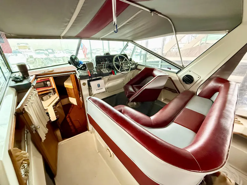 Slide: The Image of 1986 Cruisers Yachts 297 Elegante interior with red and white seating, helm, and cabin area. - 7