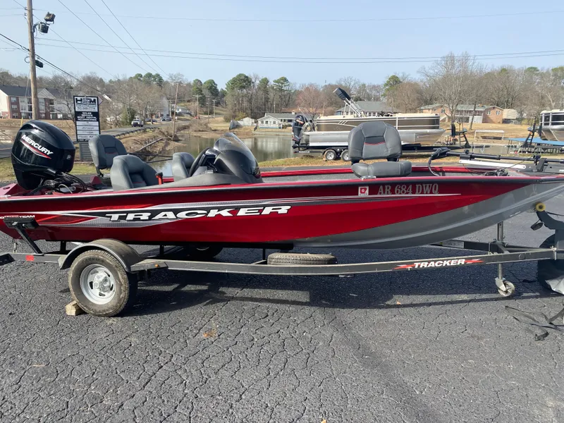 Slide: The Image of 2022 Tracker Pro Team 175 TXW boat on trailer, red and black, parked near a lake. - 6