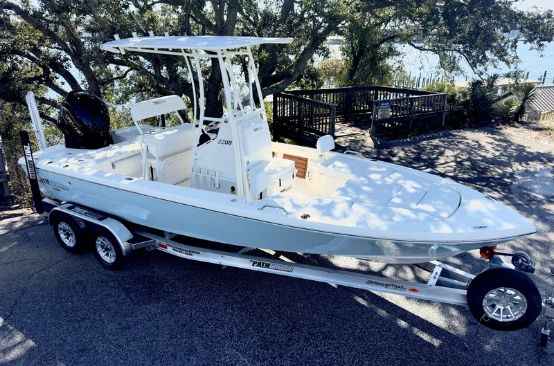 Slide: The Image of 2025 Pathfinder 2200TRS boat on trailer, parked outdoors near water. - 2