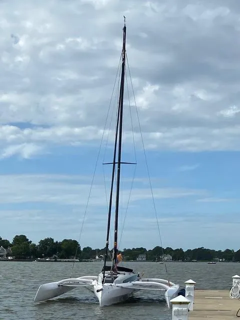 Slide: The Image of Corsair 880 trimaran sailboat docked on a calm lake under a cloudy sky. - 3