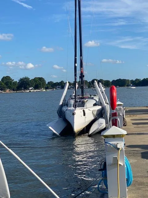 Slide: The Image of Corsair 880 trimaran docked by the shore, under a clear blue sky, 2021 model. - 6