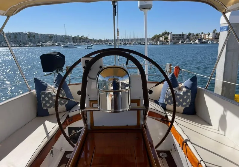 Slide: The Image of 1981 Little Harbor Cruiser cockpit with scenic marina view, featuring nautical-themed cushions. - 5