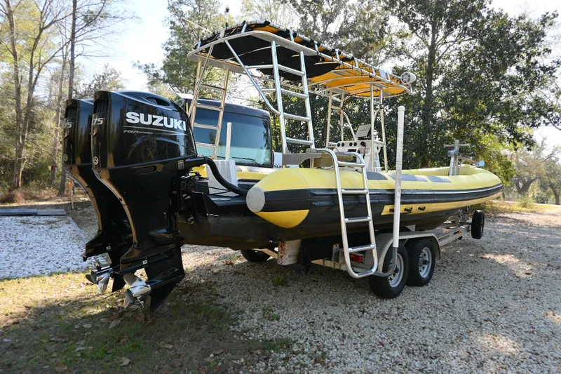 Slide: The Image of 2007 Ribcraft 9.0 boat with Suzuki engine on a trailer, parked outdoors. - 3