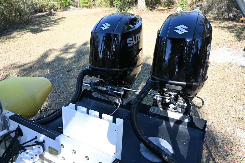 Slide: The Image of Twin Suzuki outboard motors on a 2007 Ribcraft 9.0 boat, parked on grass. - 9
