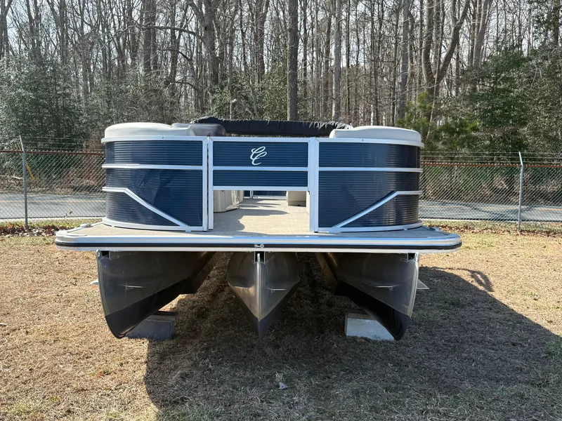 Slide: The Image of 2022 Cypress Cay Seabreeze 232 pontoon boat on grass, surrounded by trees and fence. - 2