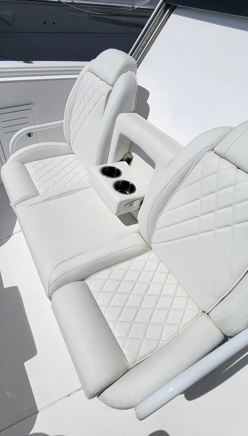 Slide: The Image of 2024 Everglades 365 Center Console boat seating with cup holders, featuring white quilted upholstery. - 13