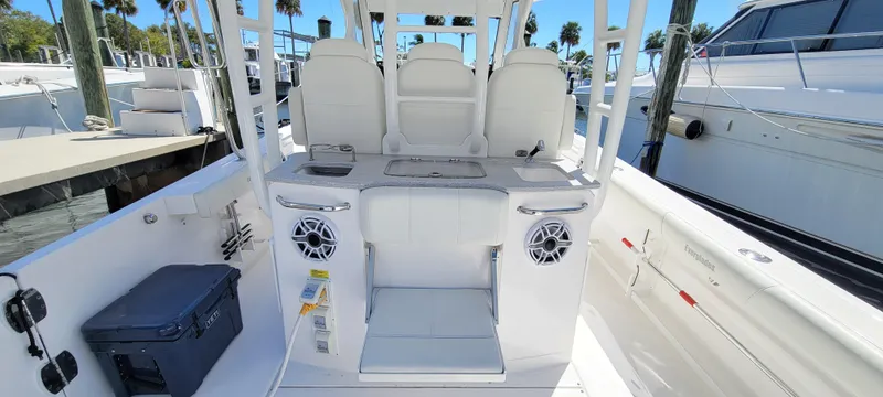 Slide: The Image of 2024 Everglades 365 Center Console boat interior with seating and speakers at a marina. - 18