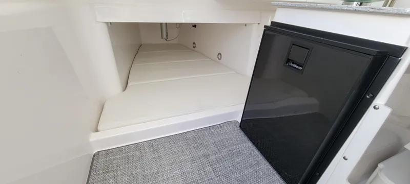 Slide: The Image of 2024 Everglades 365 Center Console cabin interior with compact fridge and cushioned sleeping area. - 20