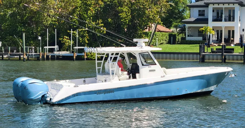 Slide: The Image of 2024 Everglades 365 Center Console boat on a calm river near waterfront homes. - 22